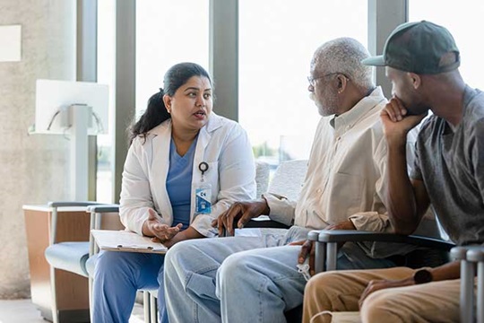 Doctor speaking with an older patient and his adult son.