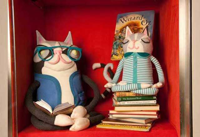 Artwork of cats wearing glasses sitting on top of books.