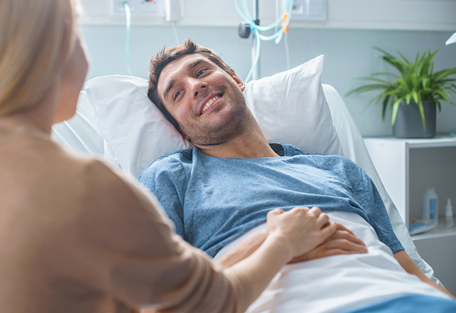 male patient in bed smiling at loved one