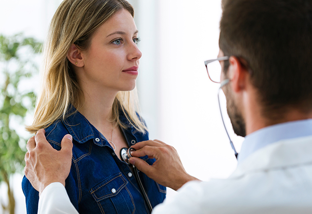 doctor listening to young woman's chest