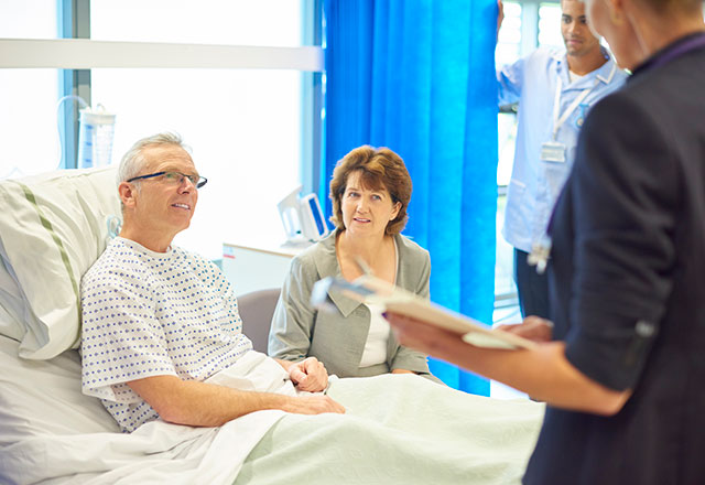 a medical team meets with a patient and his wife in his hospital room