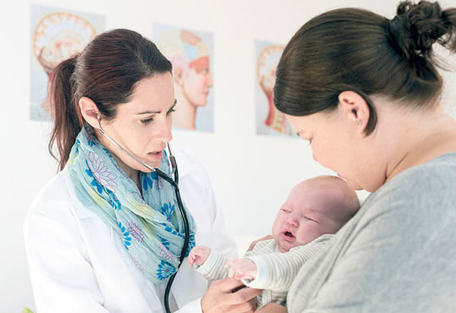 woman holding her baby speaking with a doctor