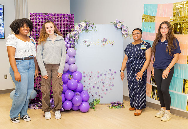 Group of young volunteers posing in front of a large thank you sign.
