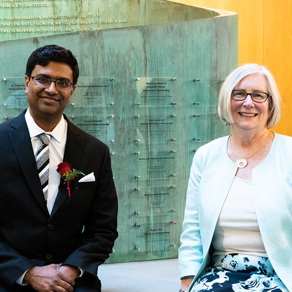 Pradeep and Sheila seated together in front of a glass wall