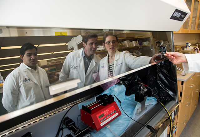 researchers huddle around tool