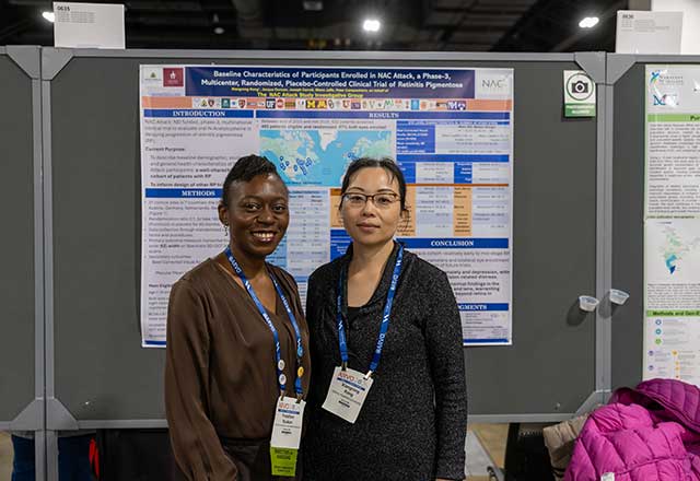 Two researchers posing together in front of a research poster