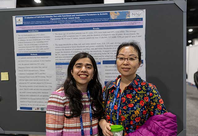 Two researchers in front of a research poster