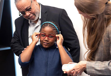 A young girl tries on glasses from Vision for Baltimore