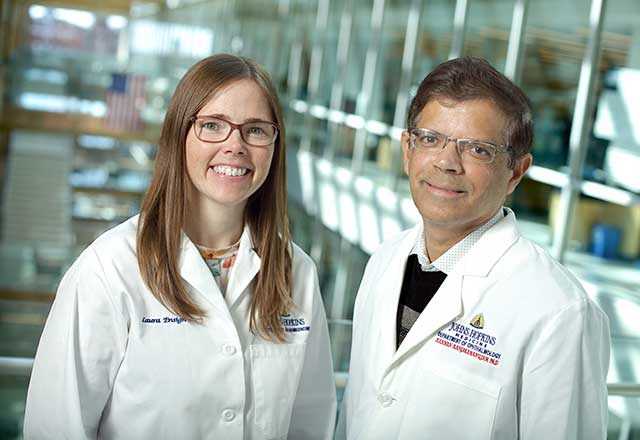 Laura Ensign and Kannan Rangaramanujam wearing white coats and smiling together