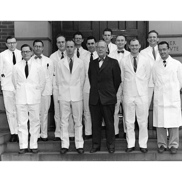 Black and white photo of resident class posing together in white suits