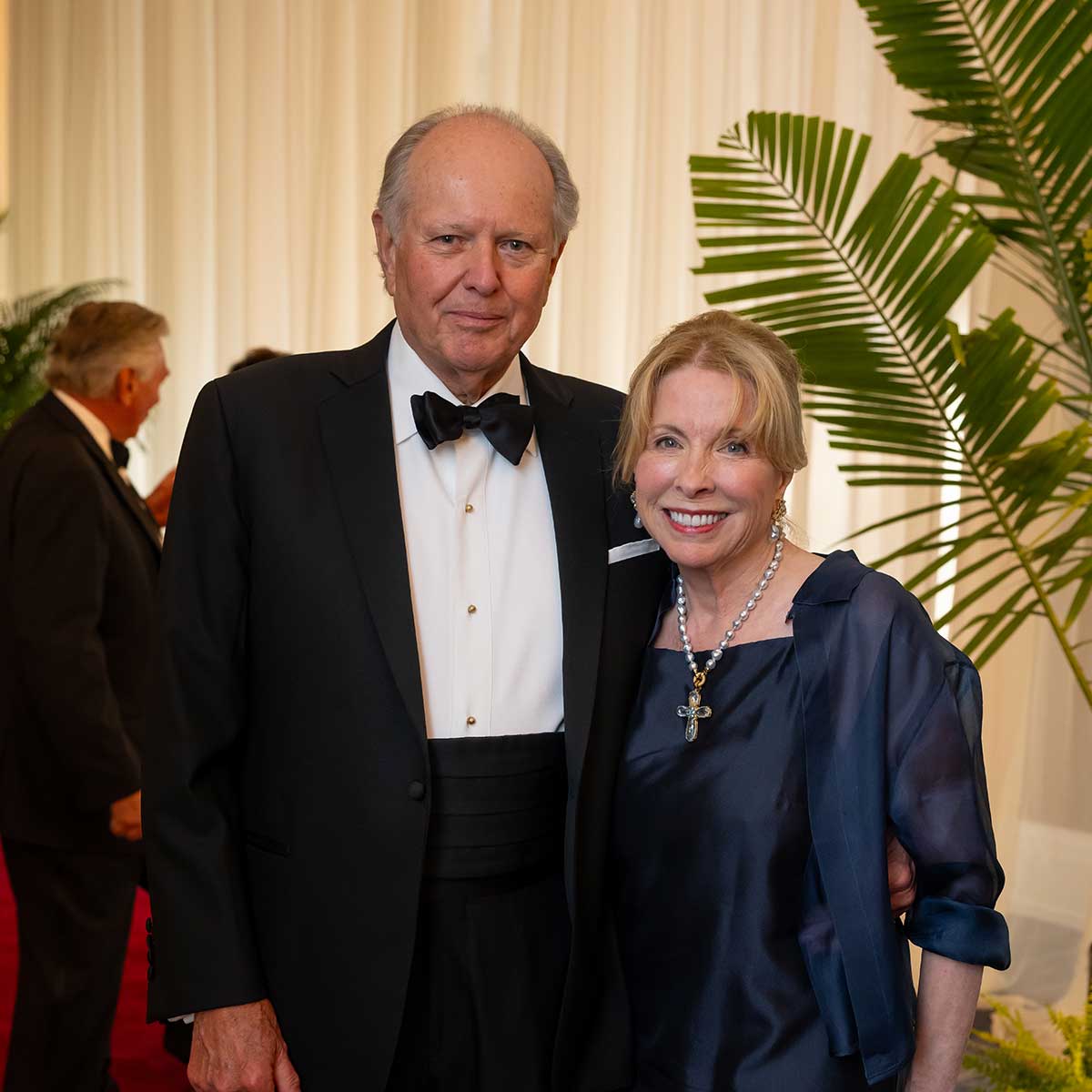 William and Jennifer Wood smiling together as they walk a red carpet