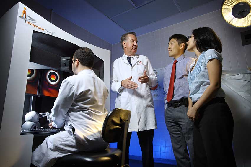 McDonnell speaks with three researchers in a lab