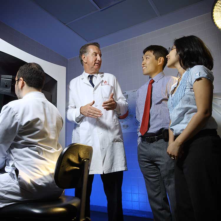 McDonnell speaks with three researchers in a lab