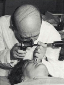 Black and white photo of Dr. Patz examining a patient's eye
