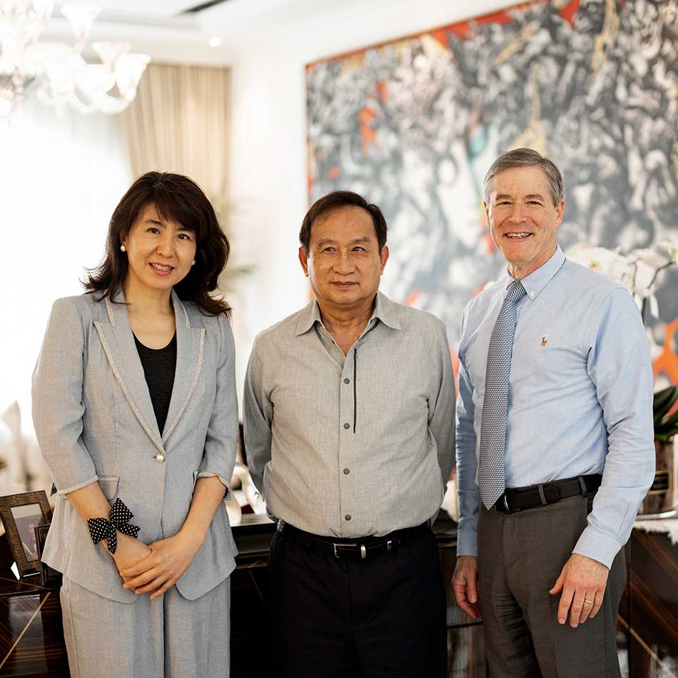 Jun Kong, Chalerm Yoovidhya and Neil Bressler smiling together in a bright living room