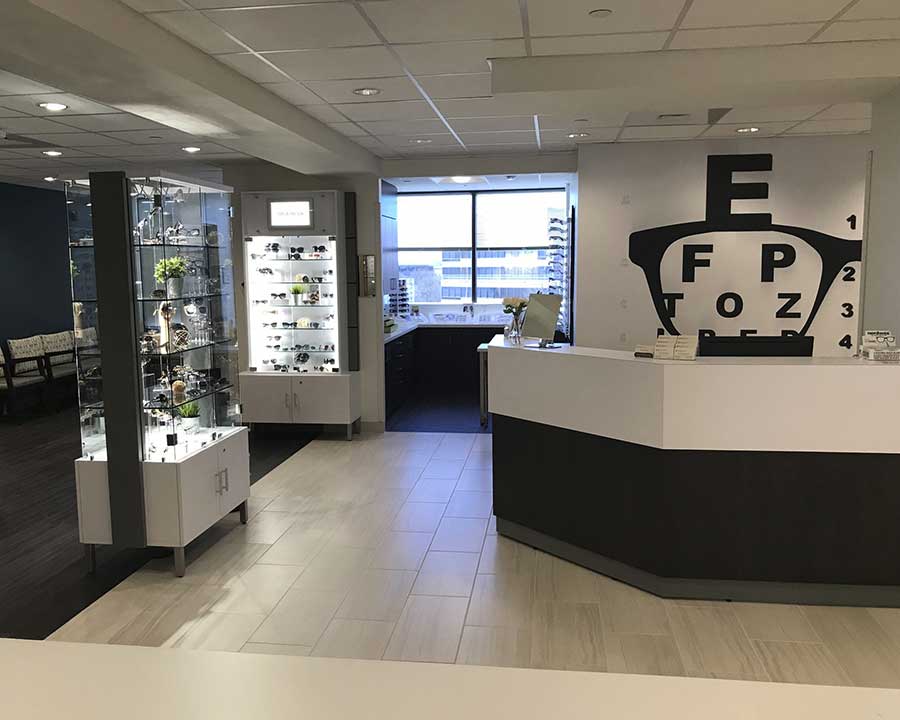 View of ophthalmology office, with glasses in a display case on the left and check in desk on the right.
