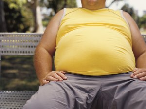 View of a man's belly as he's sitting on a bench. He's wearing a yellow shirt.