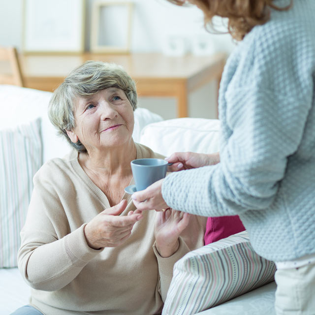 Caregiver handing woman a cup of coffee