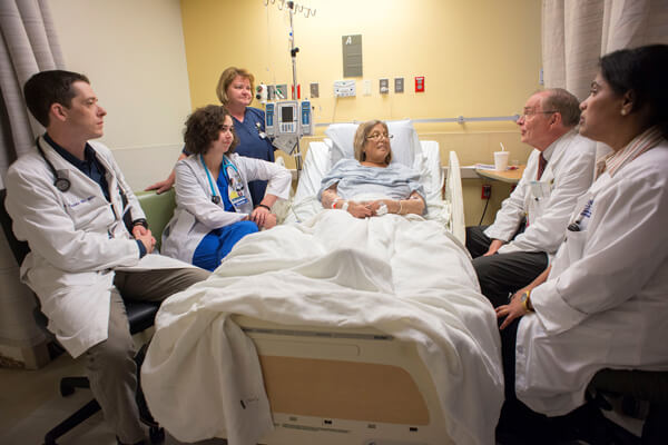 Attending and medicine residents surrounding a female hospitalized patient
