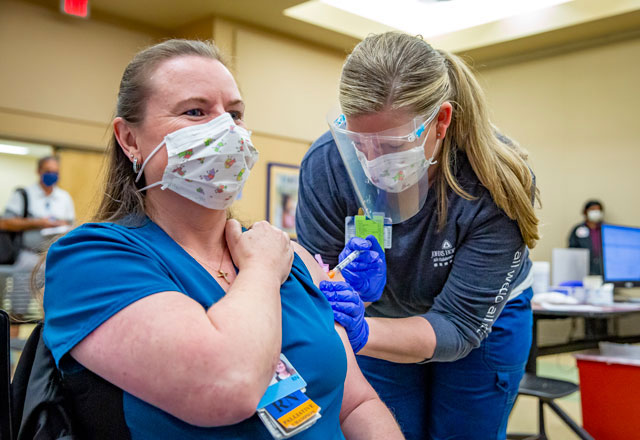 a Johns Hopkins employee administers the COVID-19 vaccine to another employee