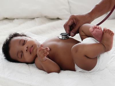 A newborn baby has its heart checked with a stethoscope