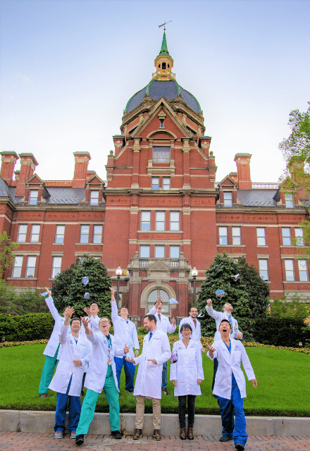 A group photo of diagnostic radiology residency graduates jumping for joy outside the dome building. 
