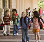 Kids carrying supplies walking into school