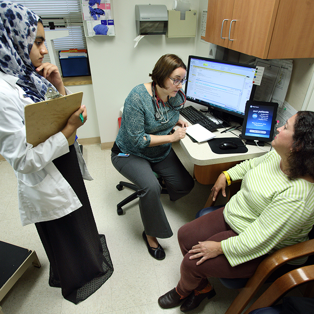 Johns Hopkins med student Anila Chaudhary observes as her instructor, internist Fernanda Porto Carreiro, discusses a medication with patient Maria Aponte. 
