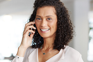 Coordenadora de cuidado fluente em Português sorridente falando com uma mulher ao telefone