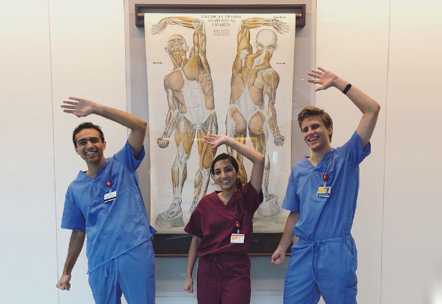 Students pose in front of an anatomical diagram