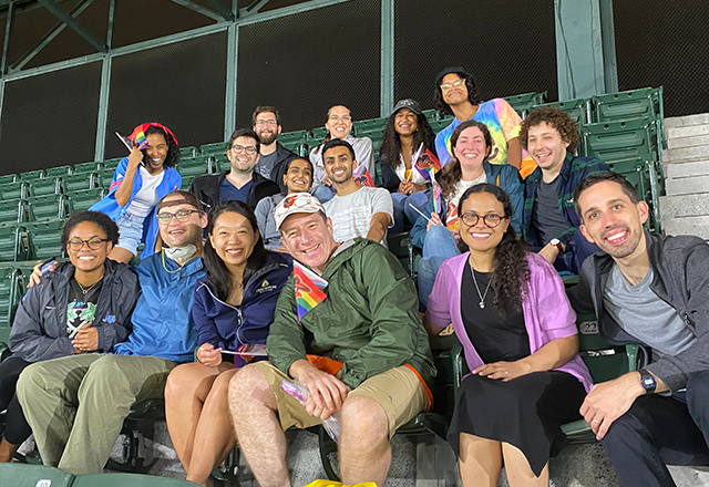 A group of residents and mentors pose together at a baseball game..