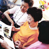 Three older Asian females looking through photo album