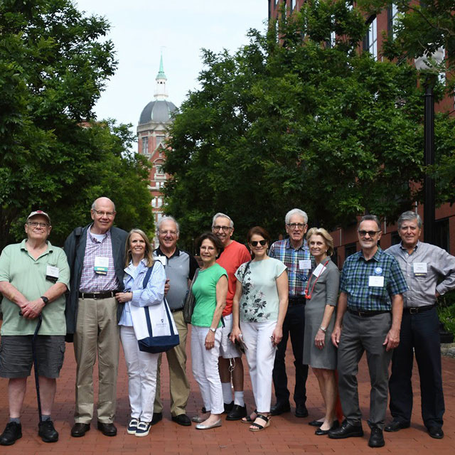Returning alumni and friends stop in front of the iconic Johns Hopkins Dome