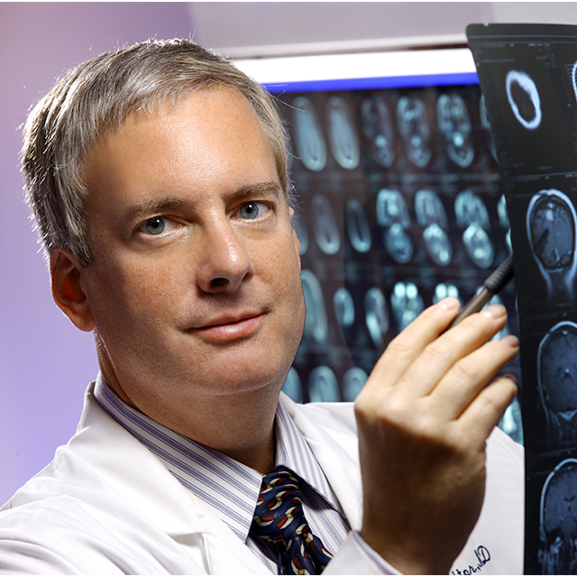Photographic portrait of Ned Sacktor with medical imagery behind him