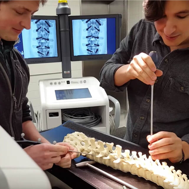 The photo shows students working on new imaging methods to improve the quality, safety, and precision of spine surgery.