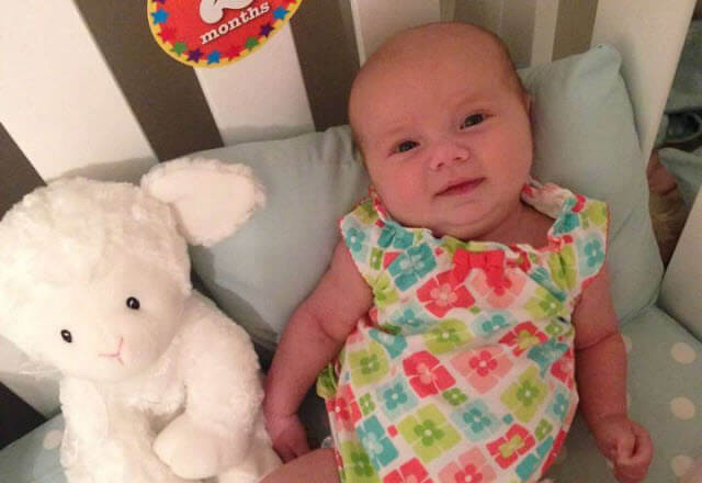Adelynn at 2 months in her crib with lamb toy