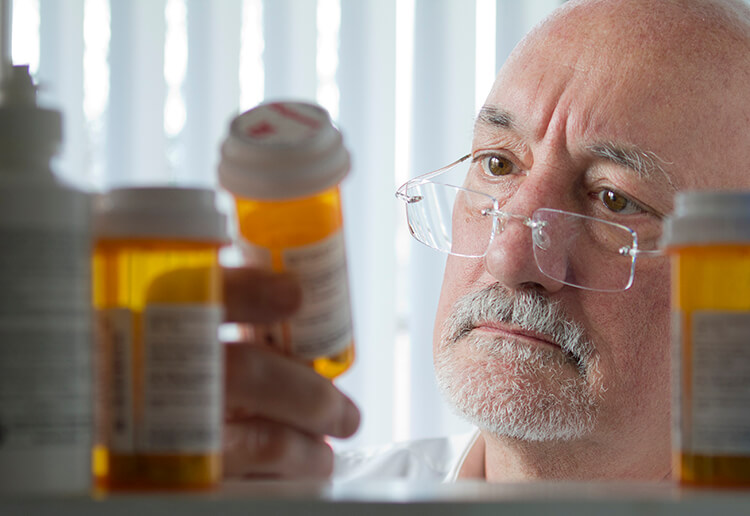 Man sorting pills in medicine cabinet