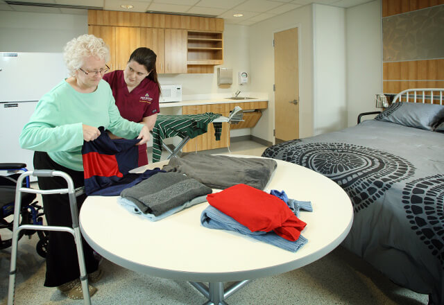 A therapist helping an old lady fold the laundry