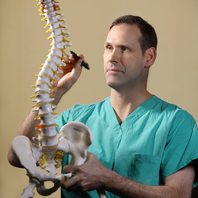 Dr. Witham examining a model of the spine.