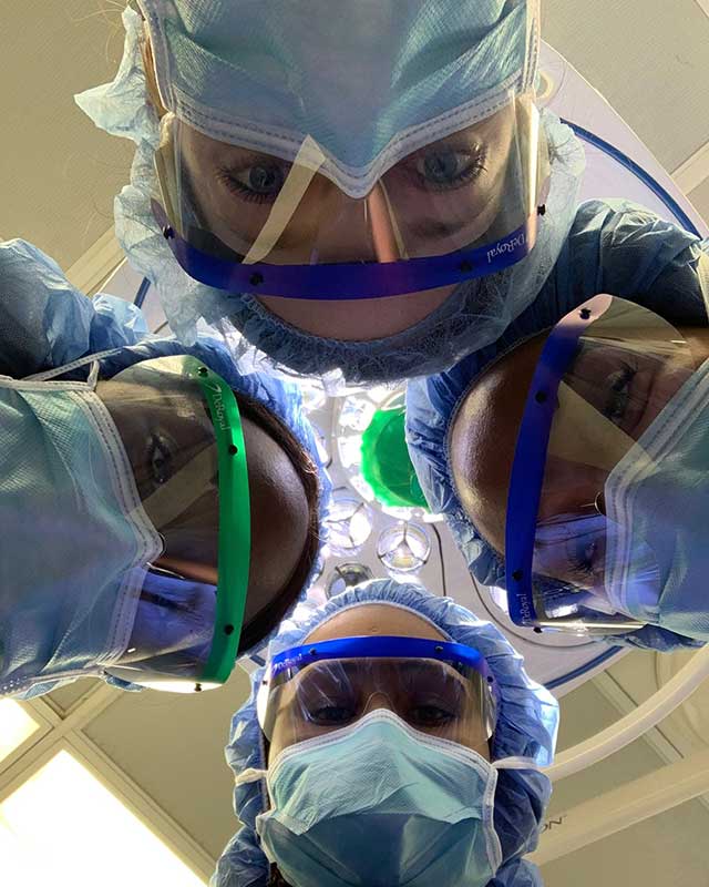 Residents pose for photo with PPE on in operating room