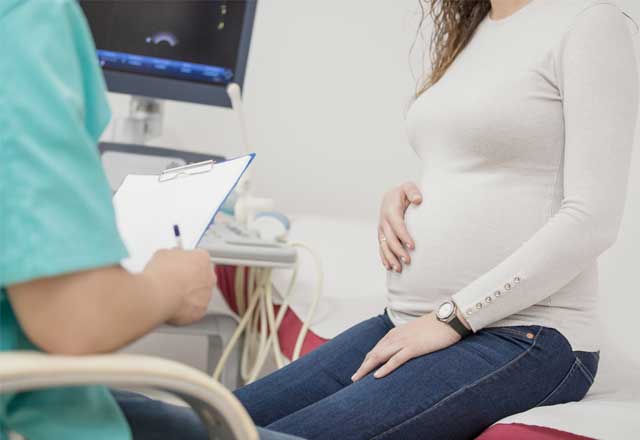 Pregnant woman sits with doctor