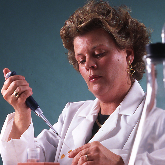 Portrait photo of Susan MacDonald holding a pipette while working in a lab