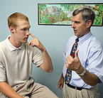 adolescent patient touching his nose during an appointment with his doctor