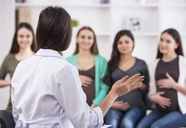 Female doctor sits with pregnant women in birthing class