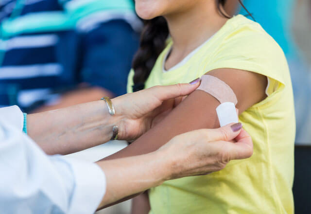 Pediatrician applies bandage to patient's arm after an immunization