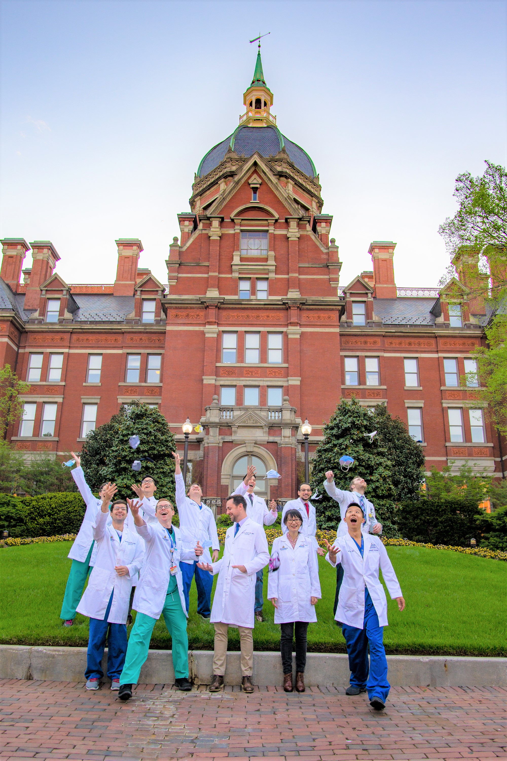 A group photo of diagnostic radiology residency graduates jumping for joy outside the dome building. 