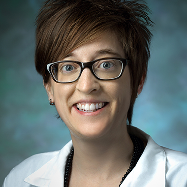 Jessica Nance, in a formal portrait, wearing a white lab coat, green blouse and black necklace.