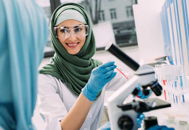 Muslim female researcher smiling in lab with microscope 