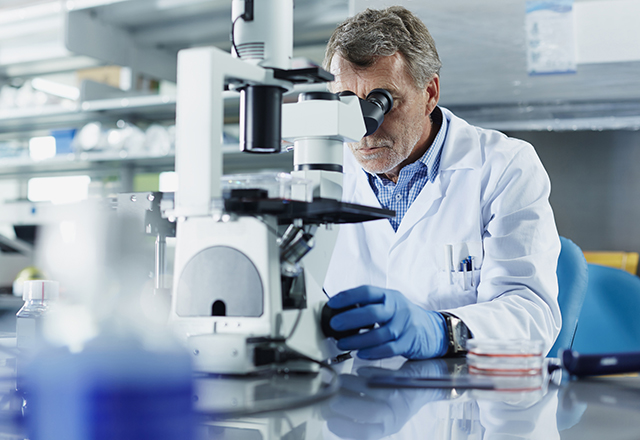 male researcher looking through microscope