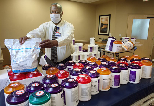 Roark Nixon stands in front of different disinfectant chemicals